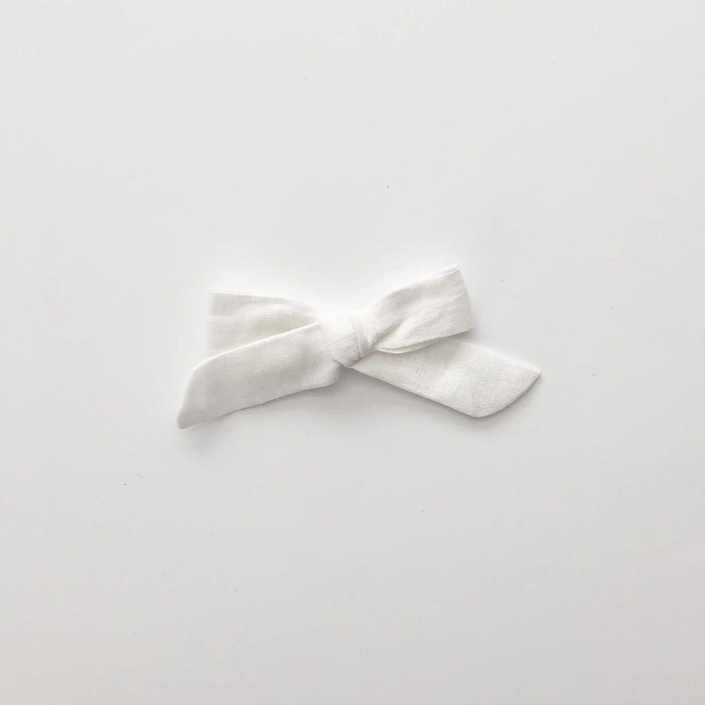 White background with the Whine Linen School Girl Bow by Wild and Free Design Co. Bow is a thin white linen style.