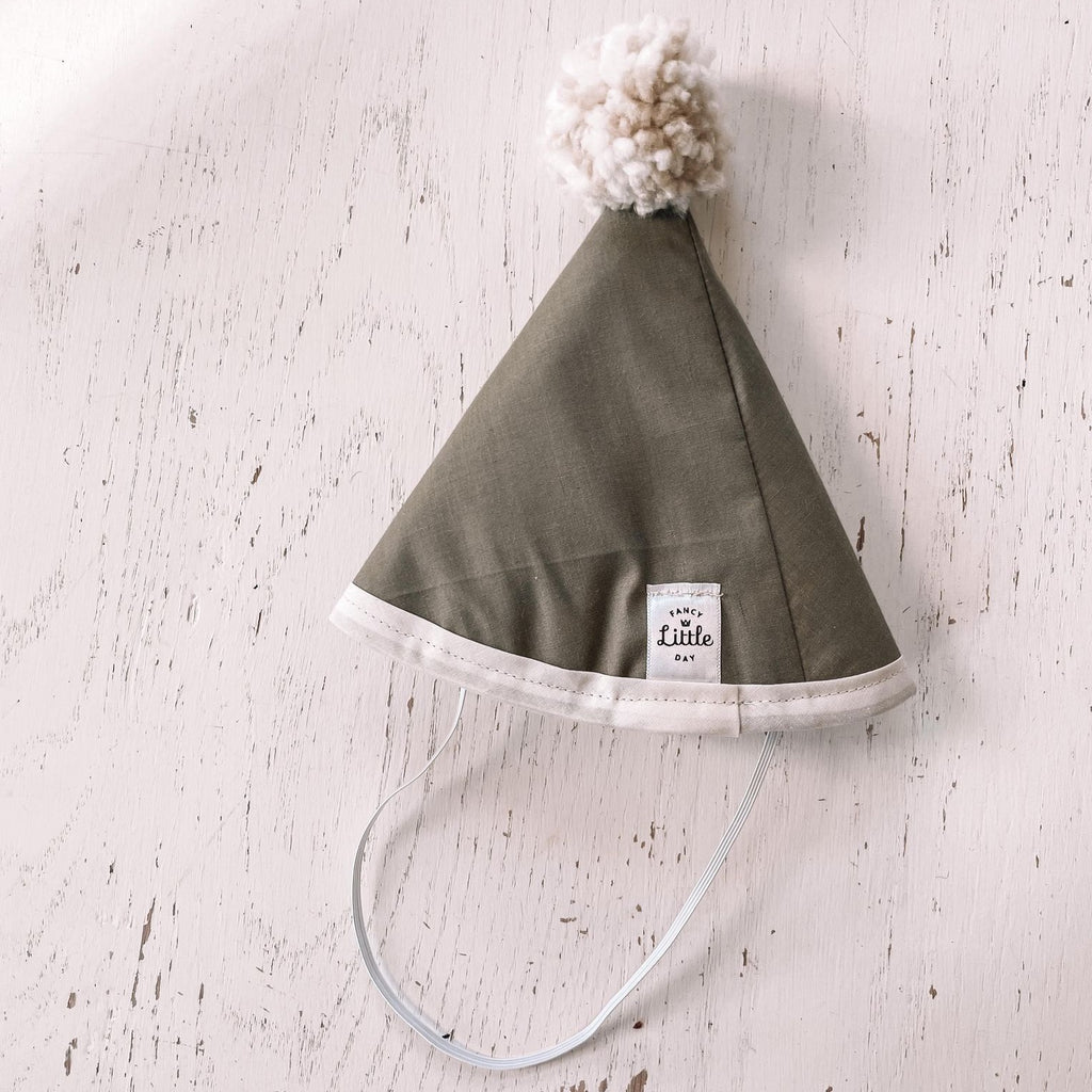 Washed white wood background with Olive Green Fabric Party Hat with Beige Pompom by Fancy Little Day. S