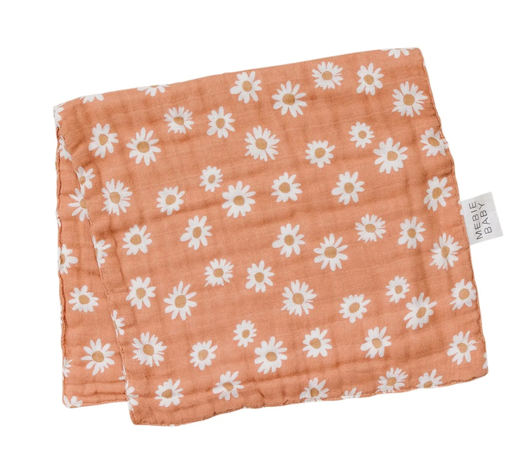 White background with a folded Arizona Daisy Burp Cloth by Mebie Baby. Burp Cloth is folded in half, is orange with daisies all over.