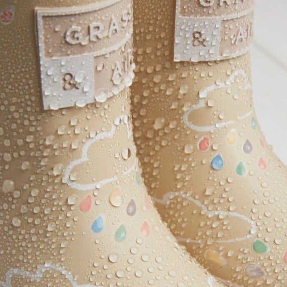 Close up of Colour Changing Rain Boots in Stone by Grass & Air. Boots are a cream colour with white clouds, and the rain drops have turned multicoloured because they're wet.