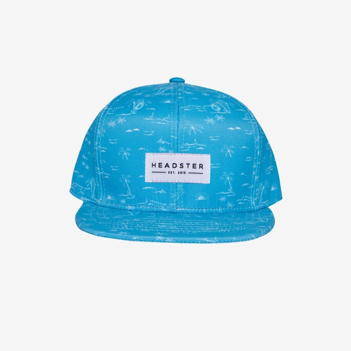 Adventure Awaits Blue Snapback by Headster with a white background and surface. 