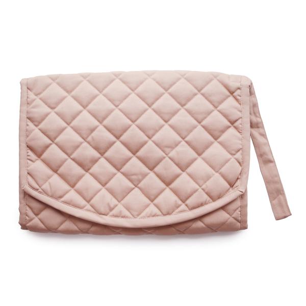 White background with the Portable Changing Pad in Blush by Mushie. Changing pad is quilted with a strap, and is blush in colour.