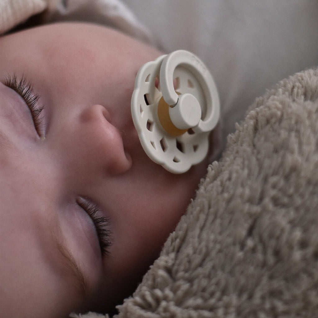 Close up of baby sleeping with the Boheme Size 1 Pacifier in Ivory by Bibs.