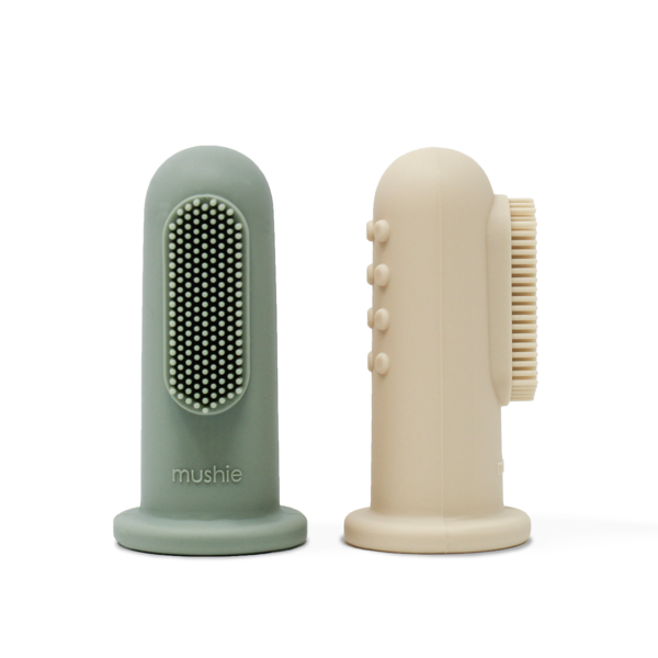 White background with Finger Toothbrush in Cambridge Blue & Shifting Sand by Mushie. This comes with 2 finger toothbrushes, 1 is a sage green colour, and the other is beige.