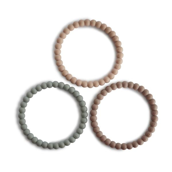 White background with Pearl Teething Bracelet 3-Pack in Clary Sage/Tuscany/Desert Sand by Mushie. These are a bracelet with a pearl style bead, in 3 different colours; a beige, cool brown, and sage.