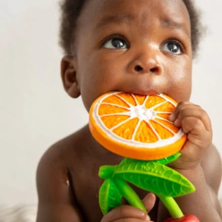 White background with a close up of a baby chewing on the Clementino The Orange Teether by Oli & Carol.
