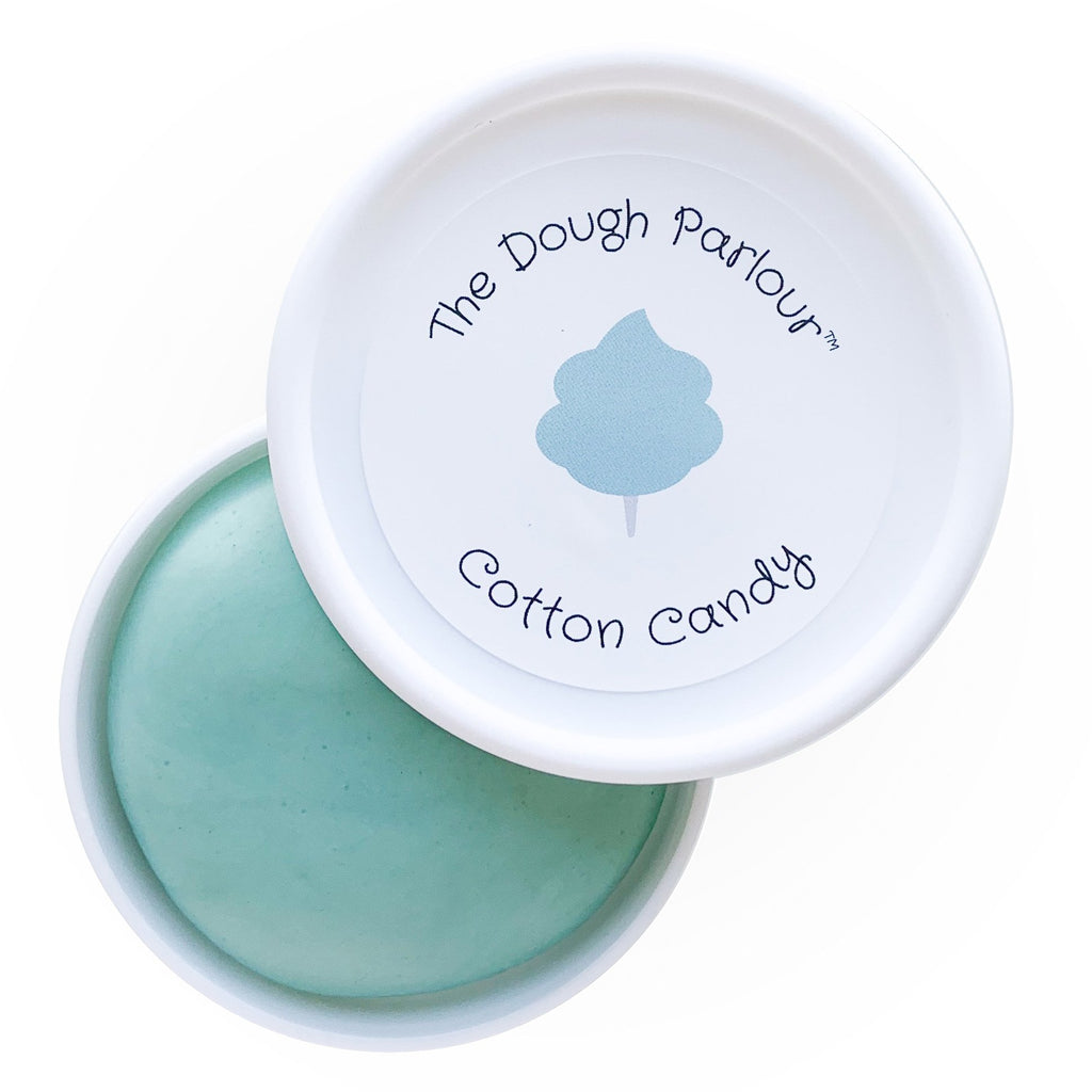 White background with Cotton Candy Play Dough by Dough Parlour, container is slightly open to show colour. Play dough comes in a white container, it's pale blue, and the lid has a sticker that says "Cotton Candy".