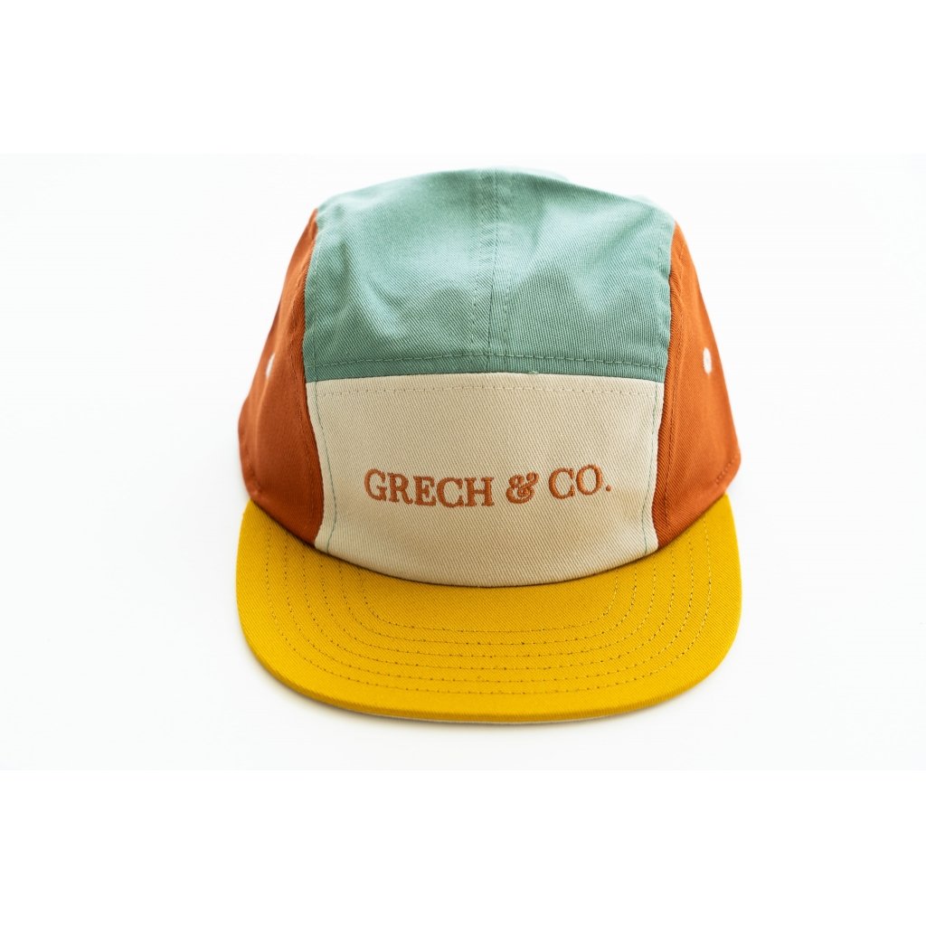 White background with 5 Panel Hat in Fern + Buff by Grech & Co. This hat is a few different colours, greeny/blue, rust, and yellow with a cream front panel with "Grech & Co." in rust across the front.