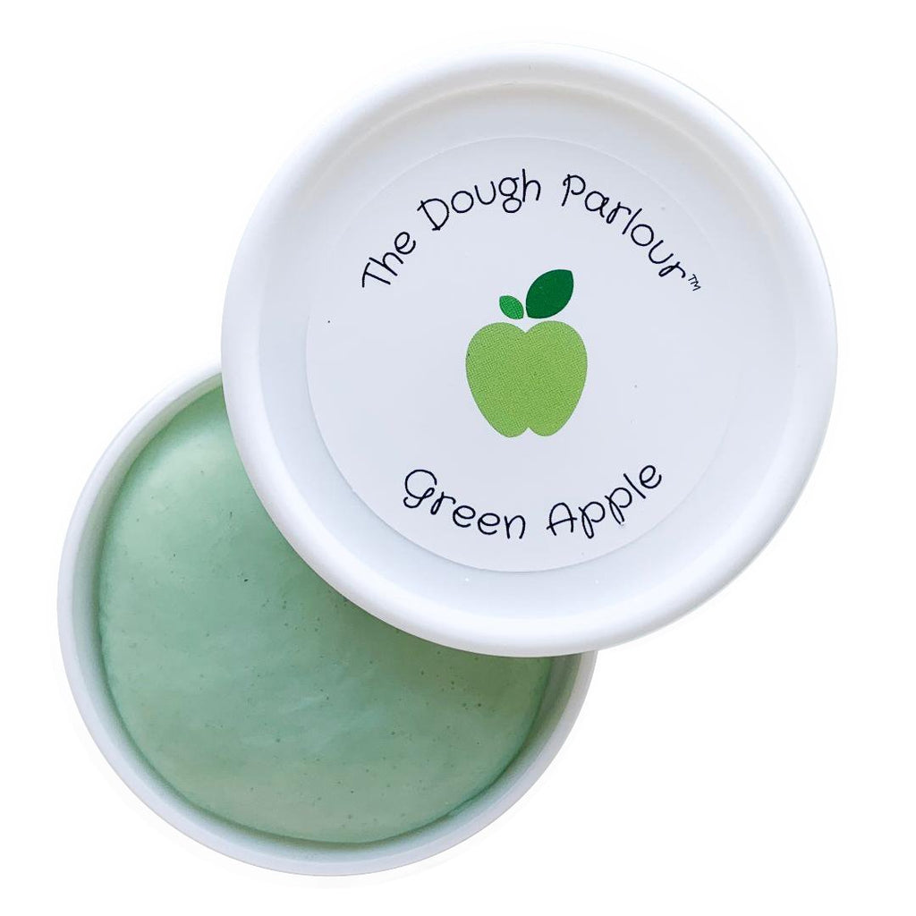 White background with an open container of Green Apple Play Dough by Dough Parlour. Colour is a soft minty green.