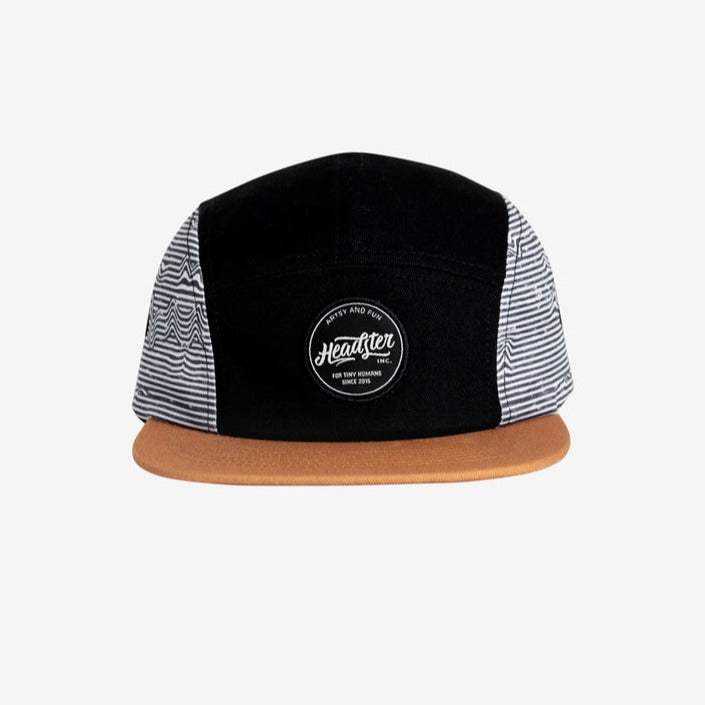 Lineup Five Panel Black by Headster with white background and surface.