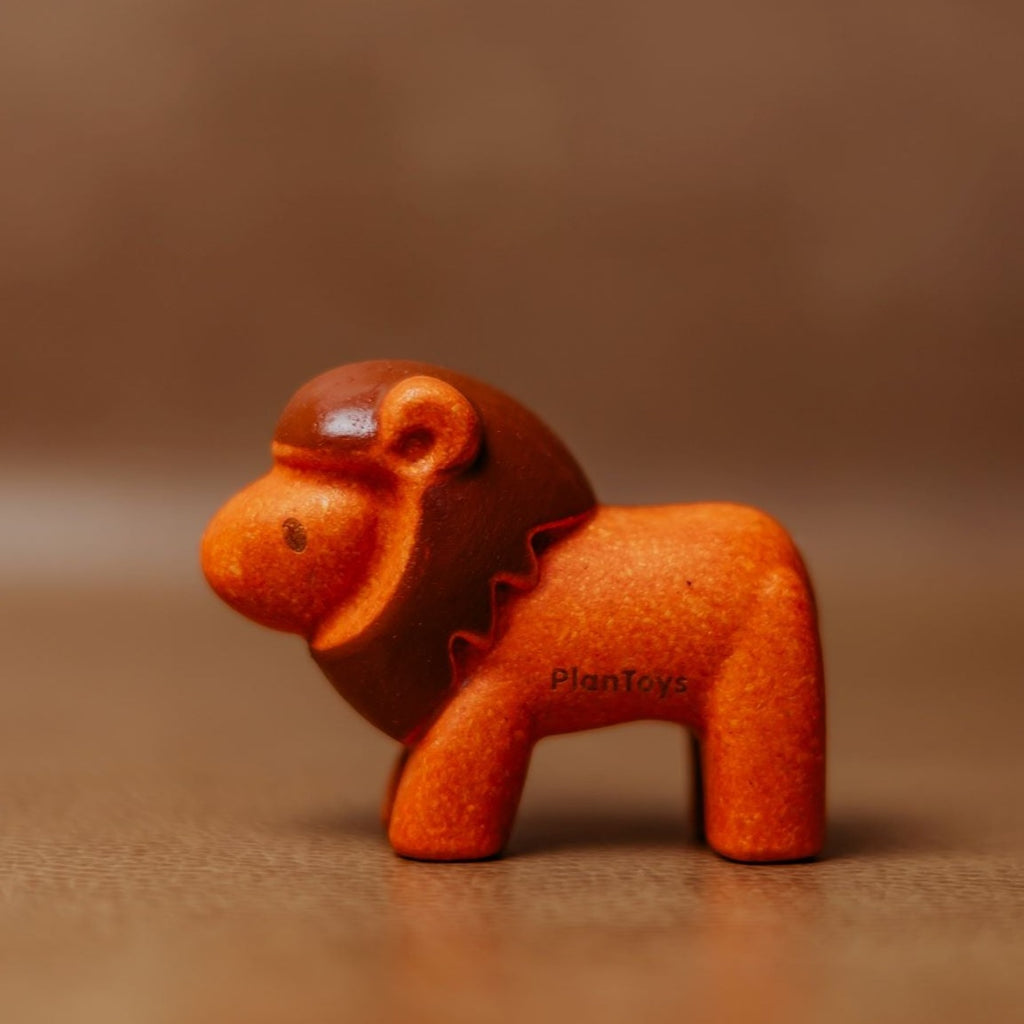 Brown background with Lion by PlanToys. Lion is an orange/red colour.