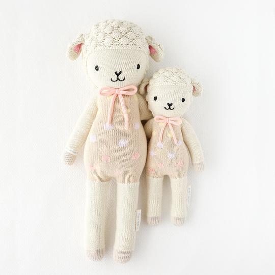 White background with Lucy The Lamb (Pastel) by Cuddle and Kind, both sizes laying side by side.