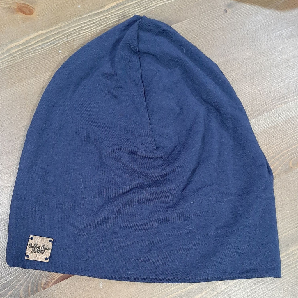 Navy Blue Beanie by Belle and Beau Baby, laid flat on a wood surface. 