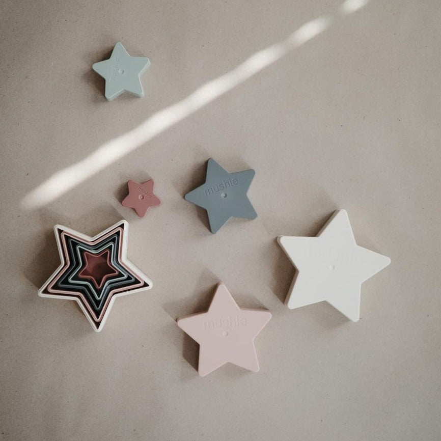 Beige background with an overhead view of the Nesting Stars Toy by Mushie, showing how they go together with a few of them laid out.