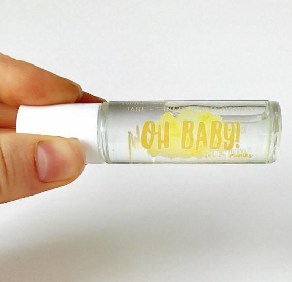 White background with hand holding Oh Baby! Baby Safe Essential Oil by Jane + Thunder. Text says "Oh baby!" in yellow.