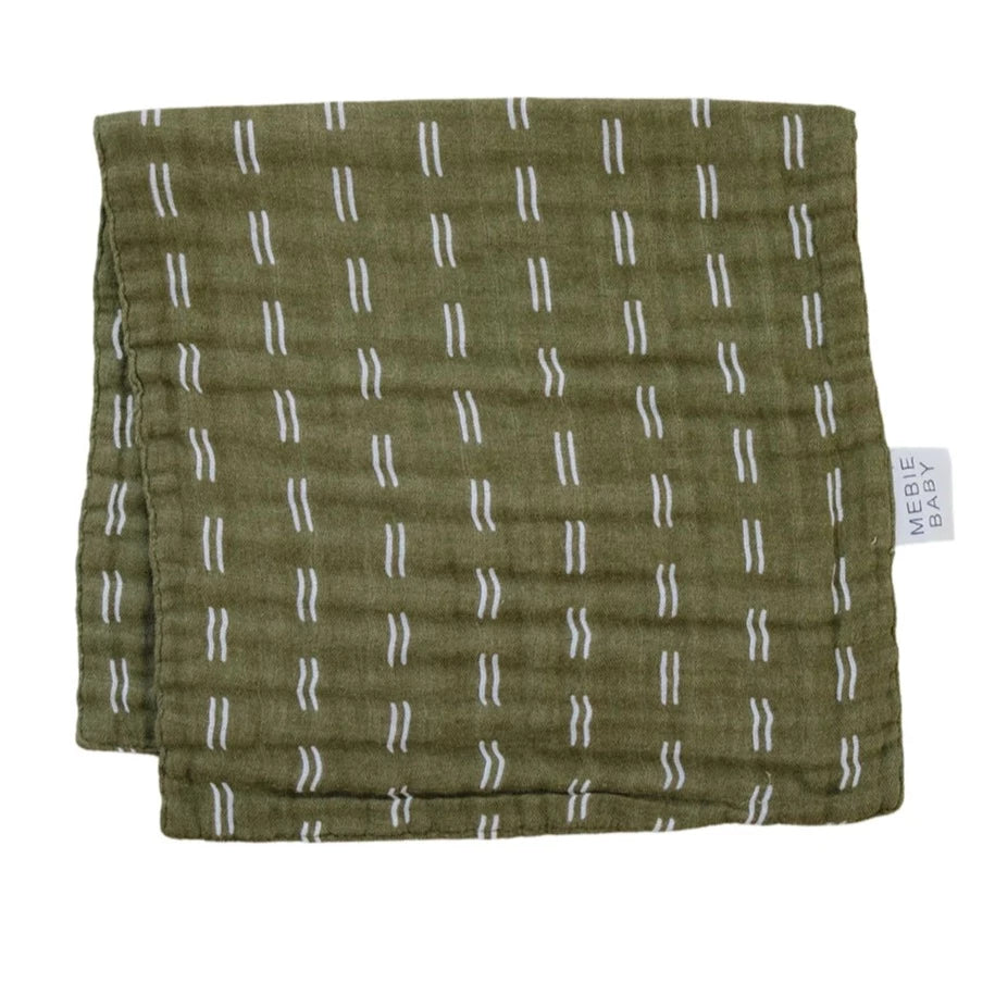 White background with Olive Strokes Burp Cloth by Mebie Baby. Burp cloth is an olive green colour with white squiggly lines, and a white tag that says "Mebie Baby".