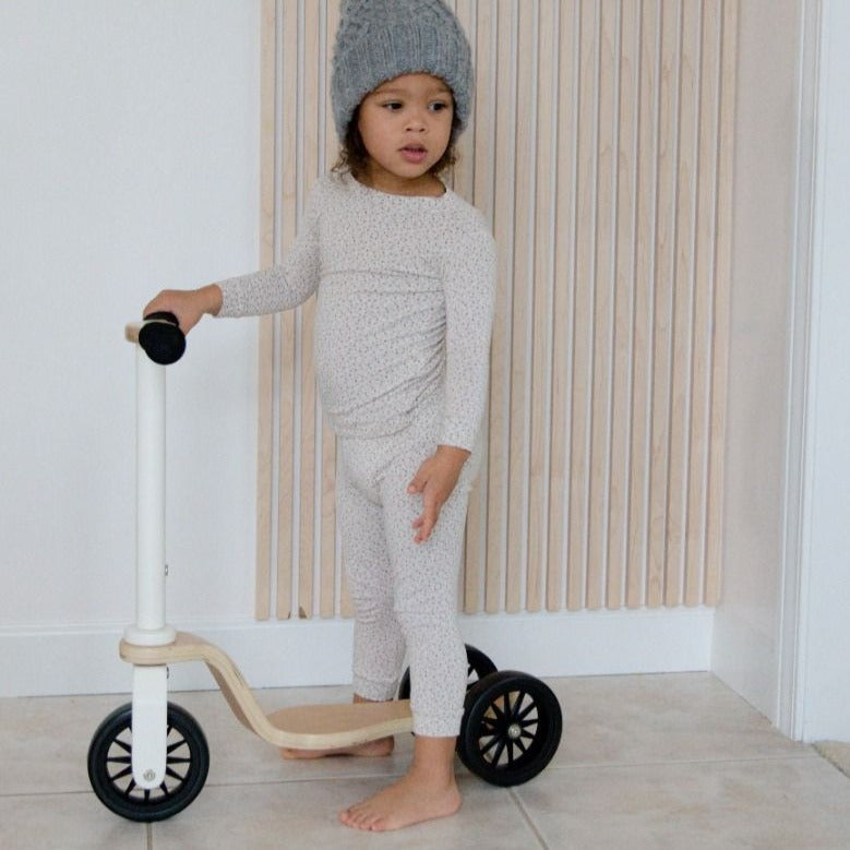 Little girl infront of white wall, standing with the Kinderscooter by Kinderfeets