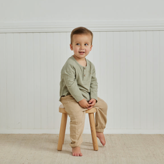 zion shirt | pistachio by Quincy Mae on little boy sitting on a wooden stool in a white studio