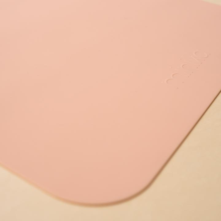 Beige background with a Silicone Placemat in Blush by Minika. Placemat is square silicone, in a blush colour.