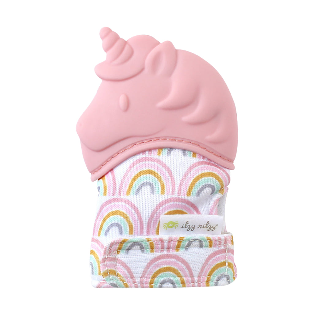 White background with the Itzy Mitt™ Silicone Teething Mitt in Unicorn by Itzy Ritzy. This mitt has a pink silicone unicorn where the fingers go, and the body is white with pink rainbows all over, made out of a crinkly material.