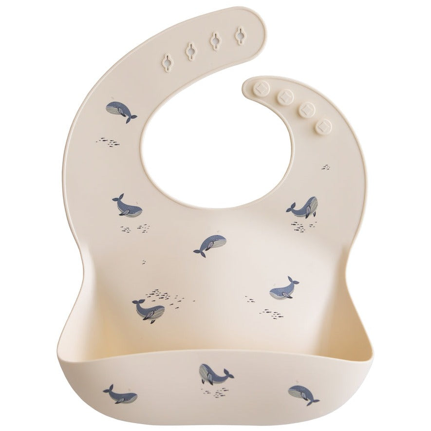 Silicone Bibs by Mushie in Whales, white background. 