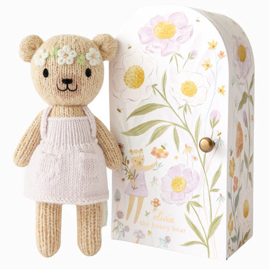 Brown bear with white floral headband standing beside floral box