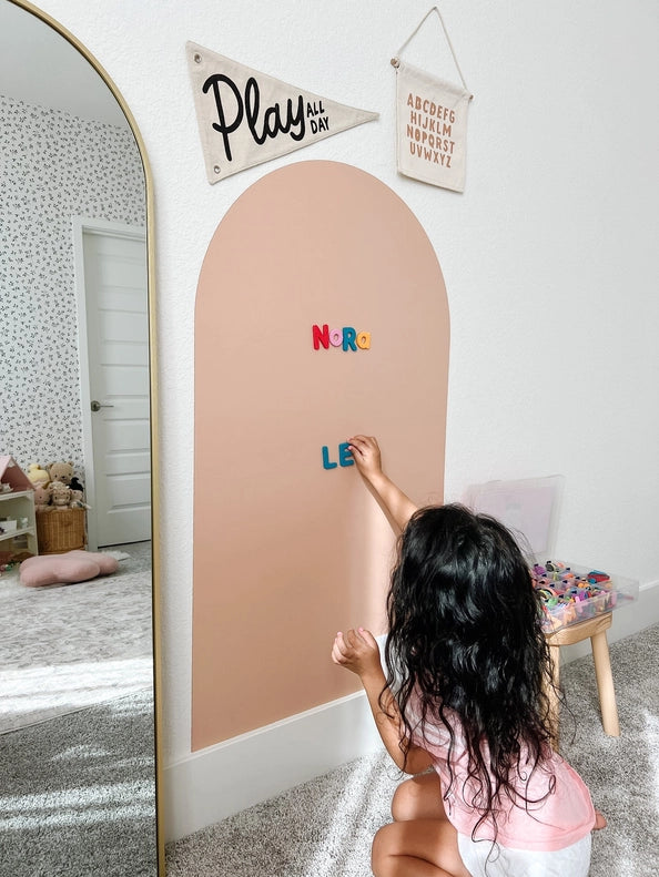 little girl with letters on blush magnetic board with m irror next to it 