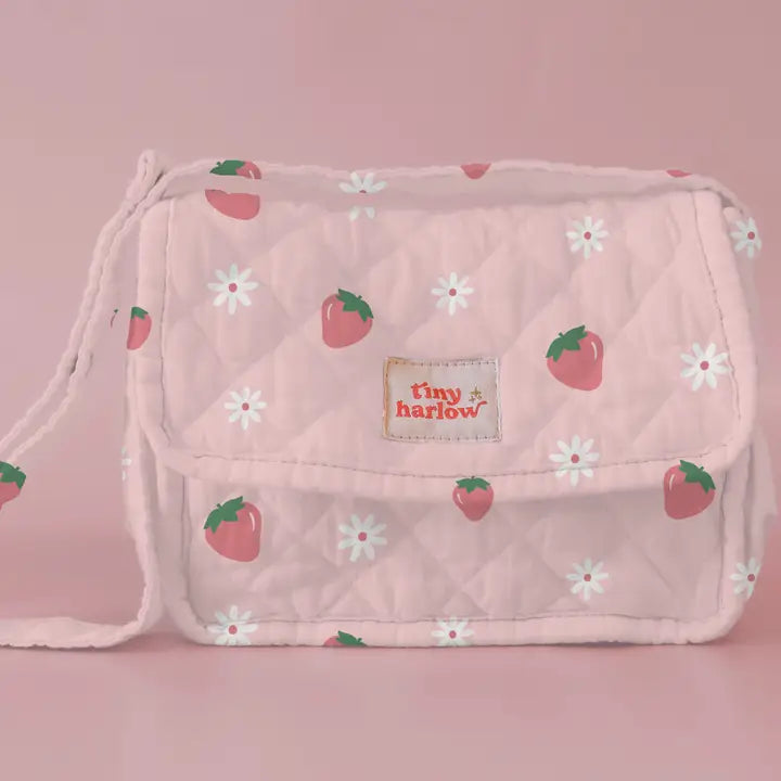 flatlay of strawberry bag on pink background 