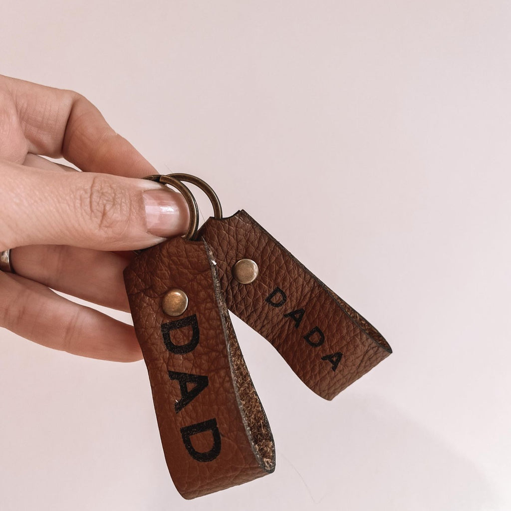 DAD | DADA | DADDY Leather Keychain by Petit Nordique held against white background