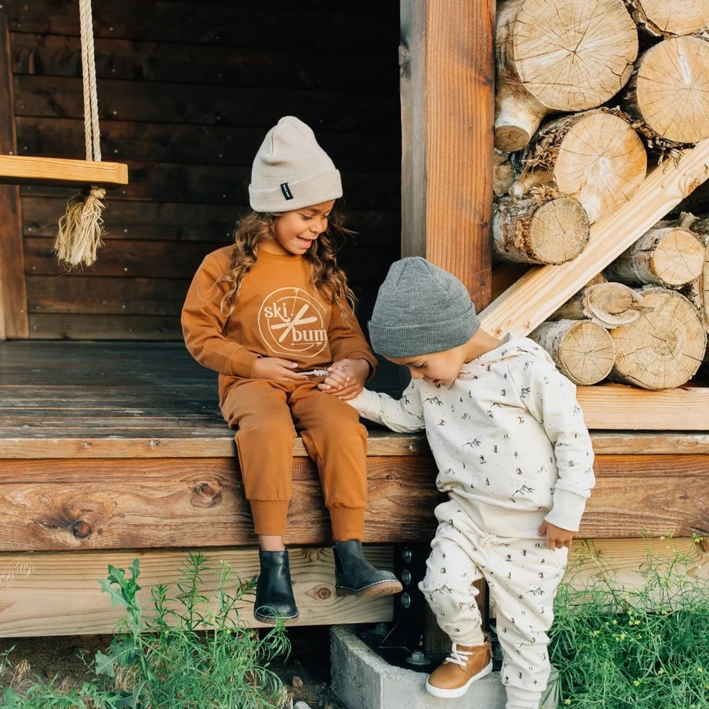 2 kids outside on wood deck with logs 