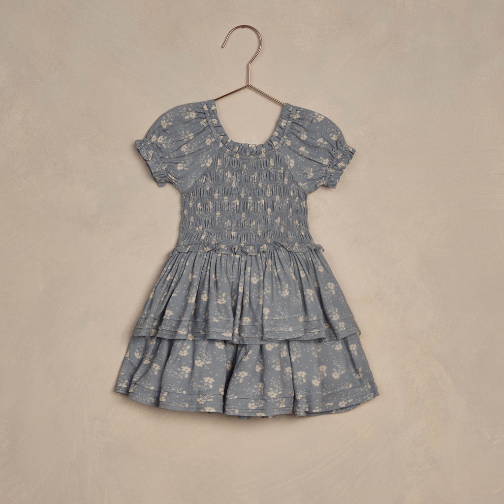 flatlay of blue floral dress on hanger beige background 