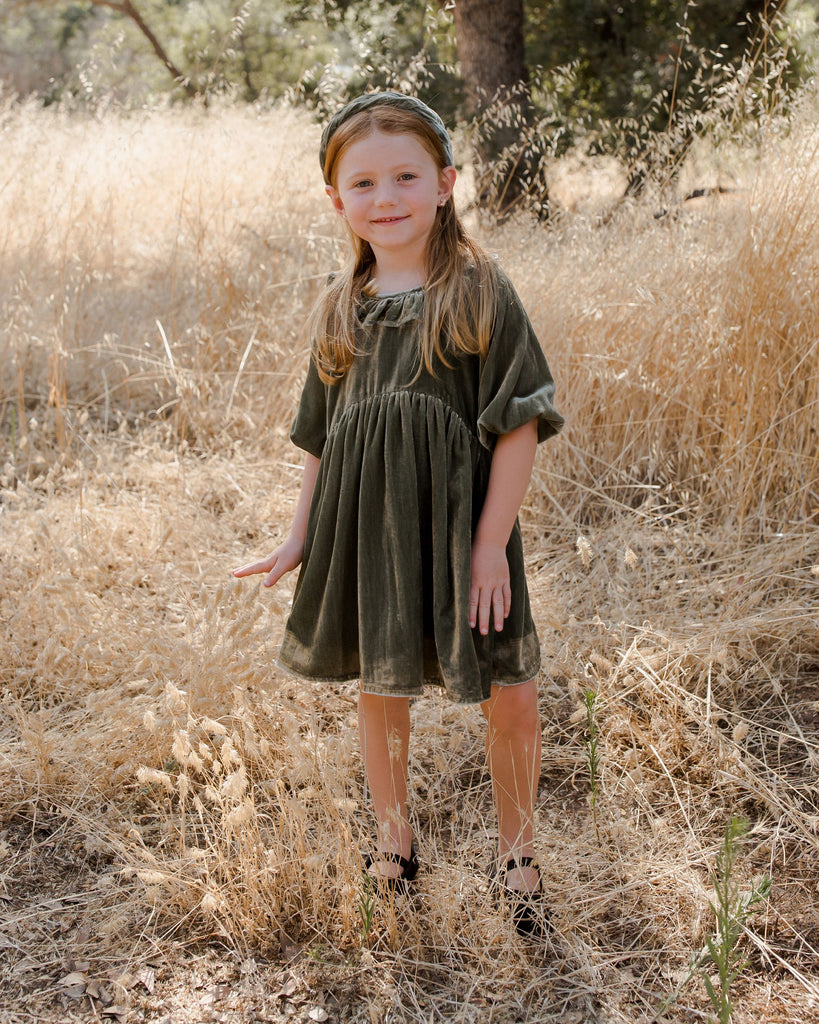 girl wearing pine dress and headband in forest 