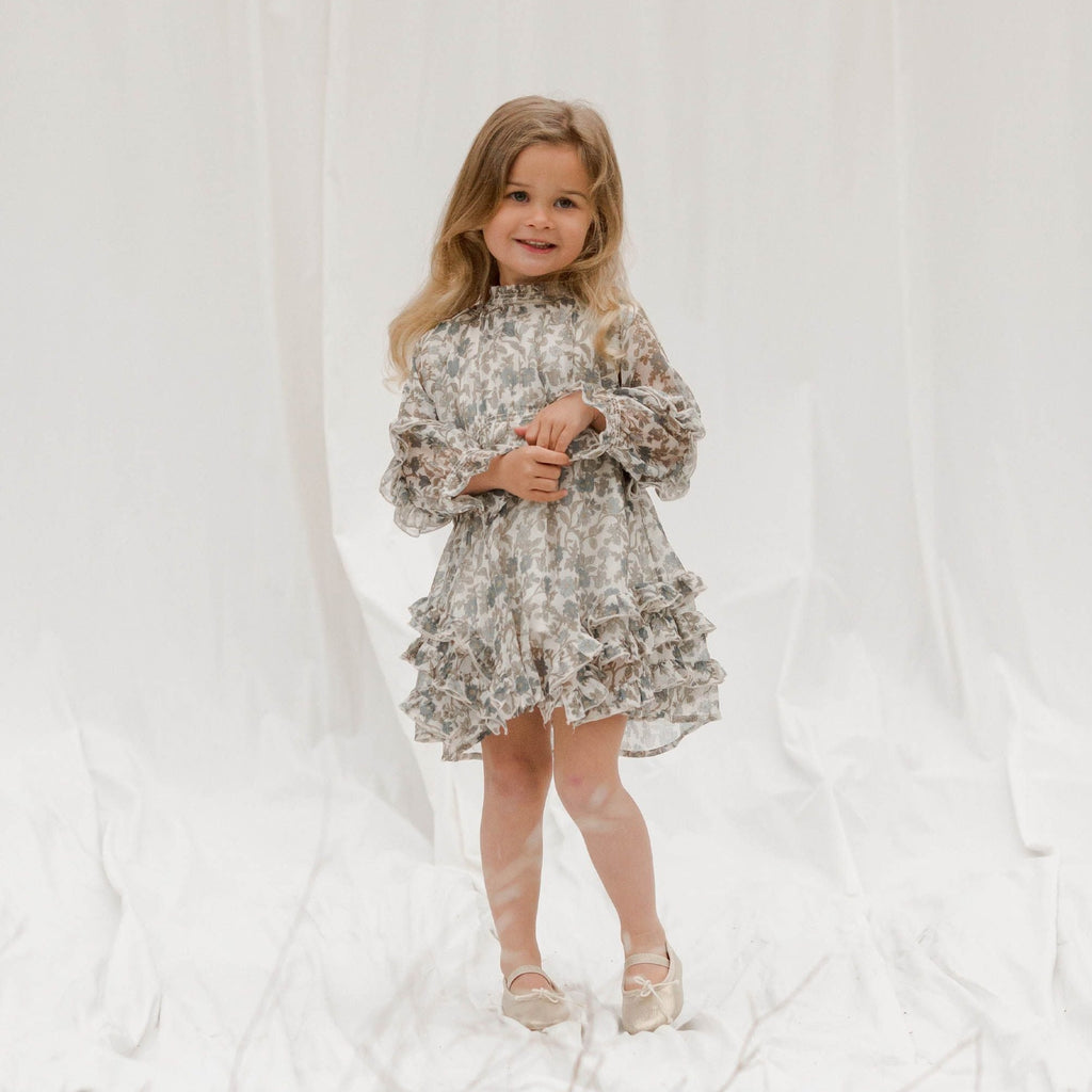 little girl on white sheet with shoes blond hair wearing dress