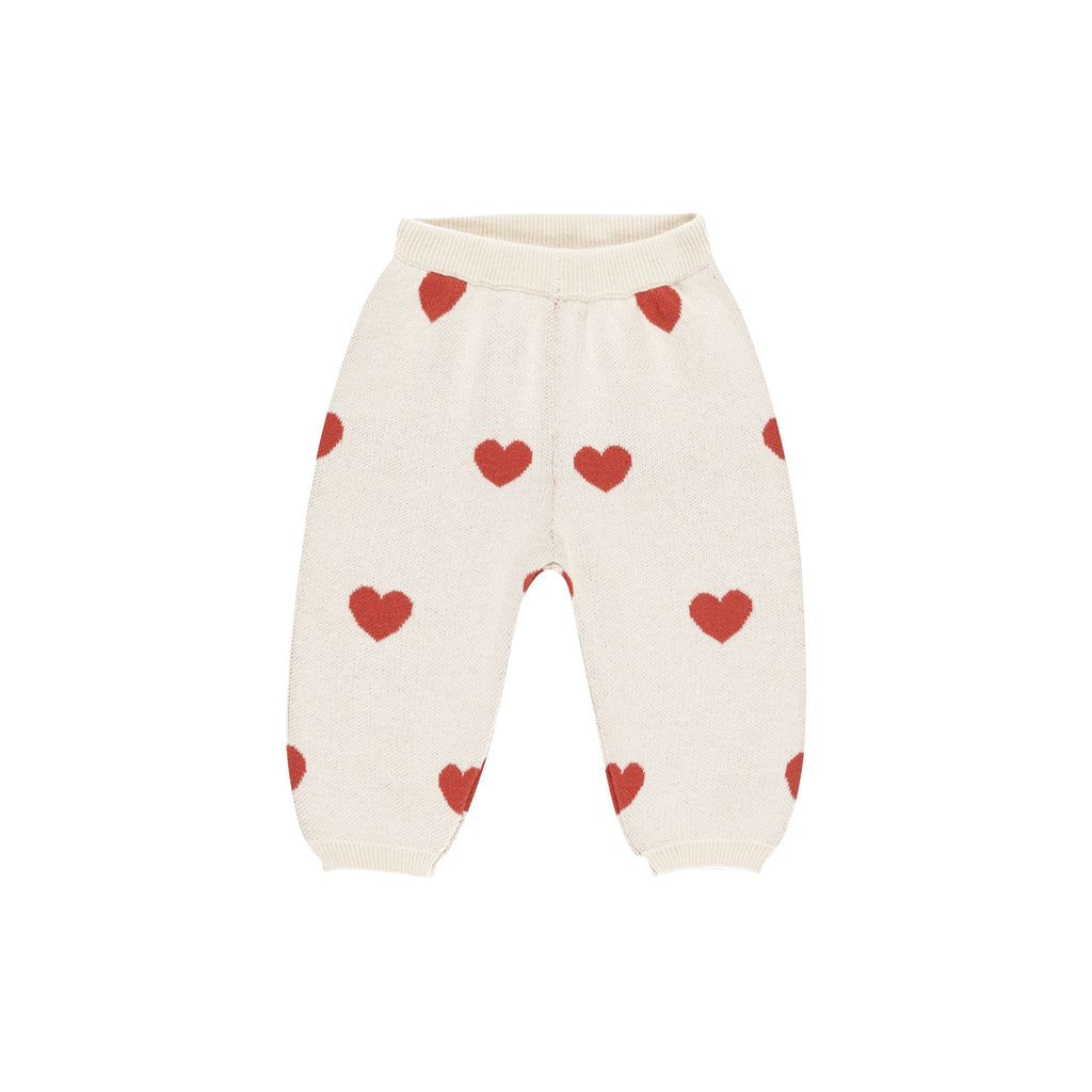 flatlay of knit ivory pant with red hearts on white background 