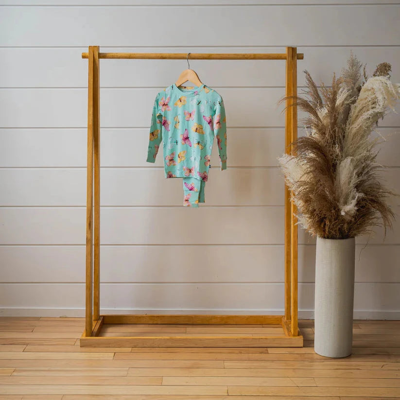 butterfly PJ set on wood dowel with plant next to it 