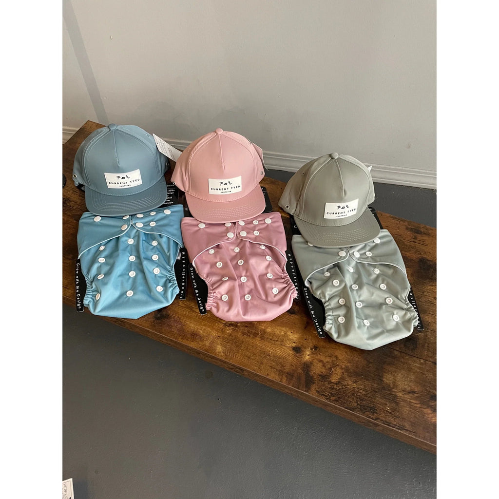 flatlay of hats with swim diapers on wood bench 