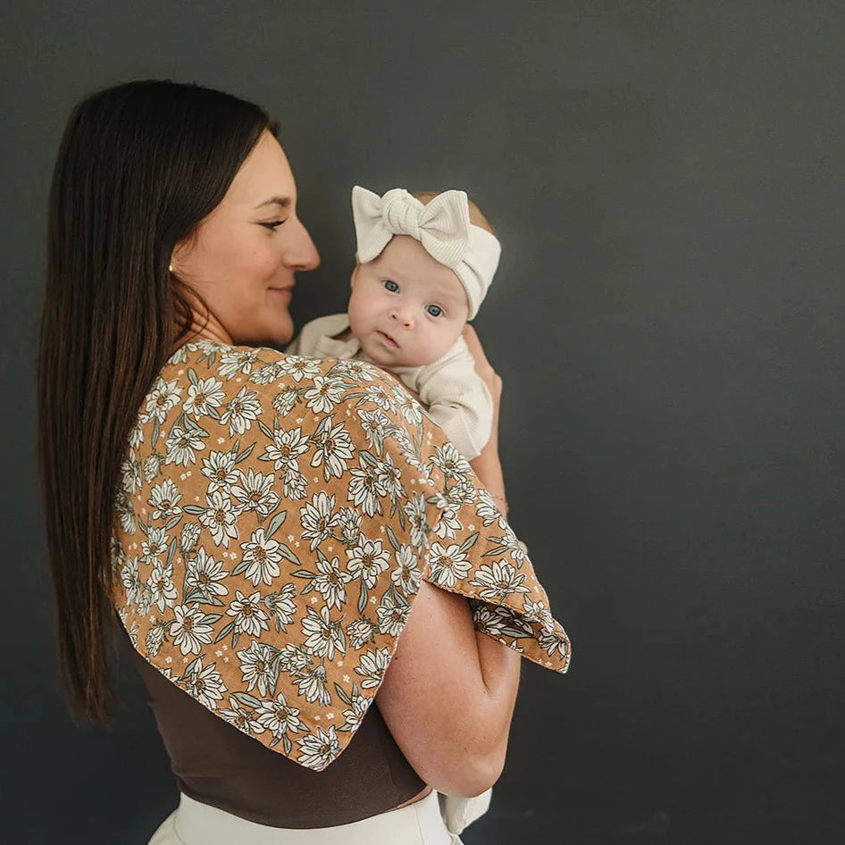Magnolia Burp Cloth by Mebie Baby mom smiling with long brown hair holding baby girl on shoulder against black background