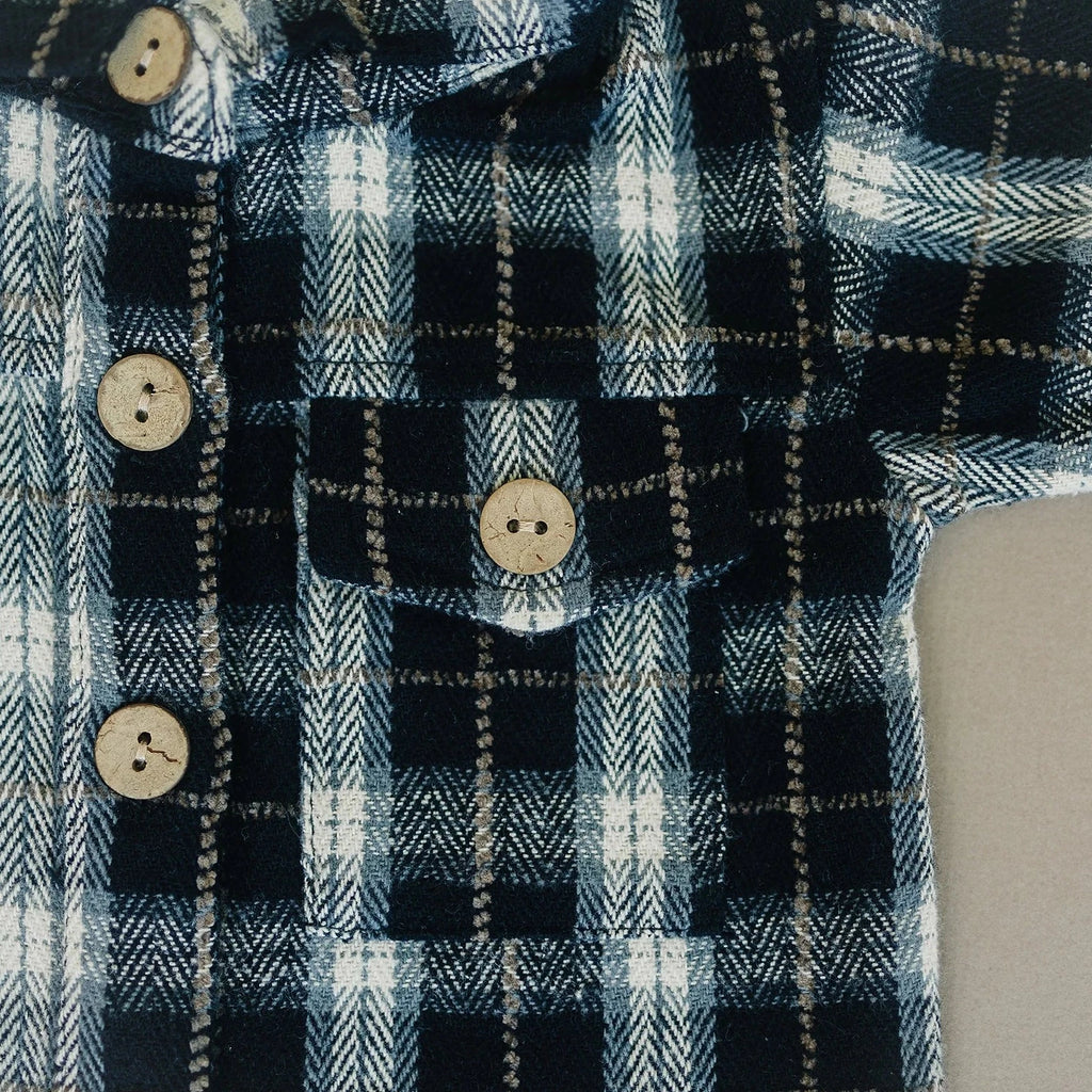 close up of buttons and plaid shirt flatlay