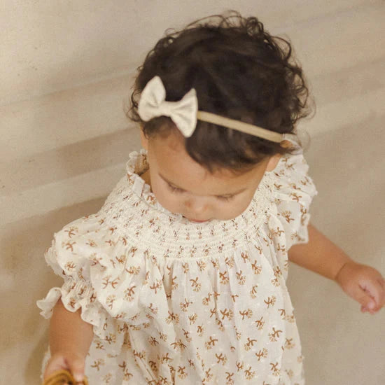 bow on little girl in floral romper holding basket 