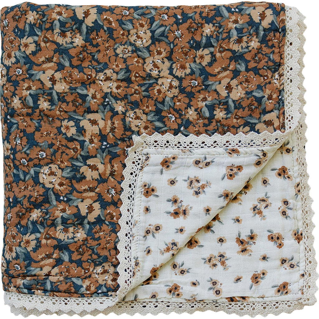 flatlay of autumn bloom quilt with lace on white background 