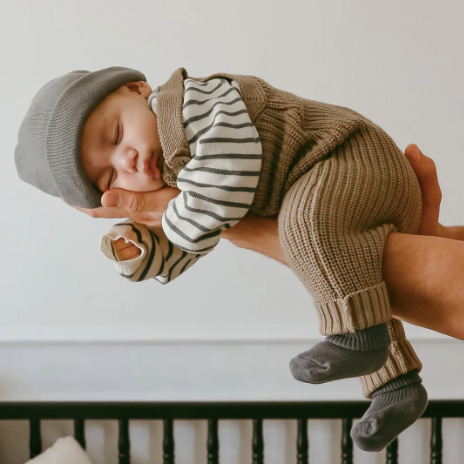Thomas Knitted Onepiece | Jamie Kay on sleeping newborn baby held up in arms 