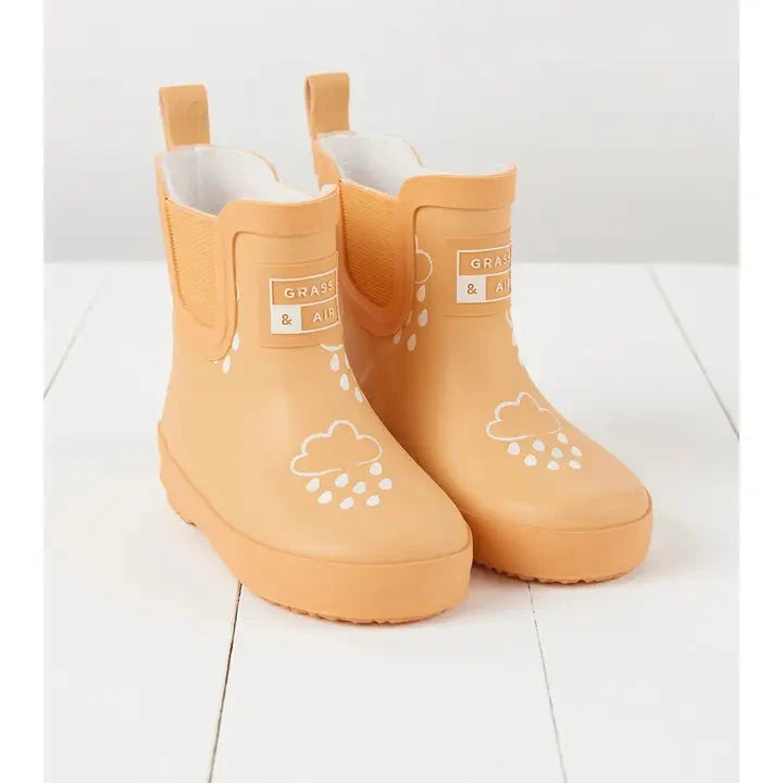 flatlay of peach boot on white background on white board floors 