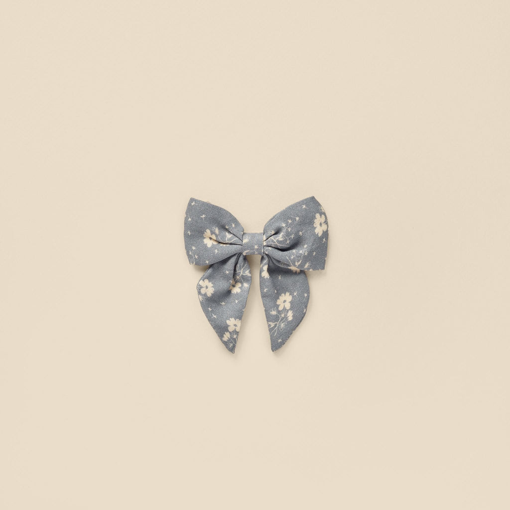 flatlay of blue floral bow on beige background 