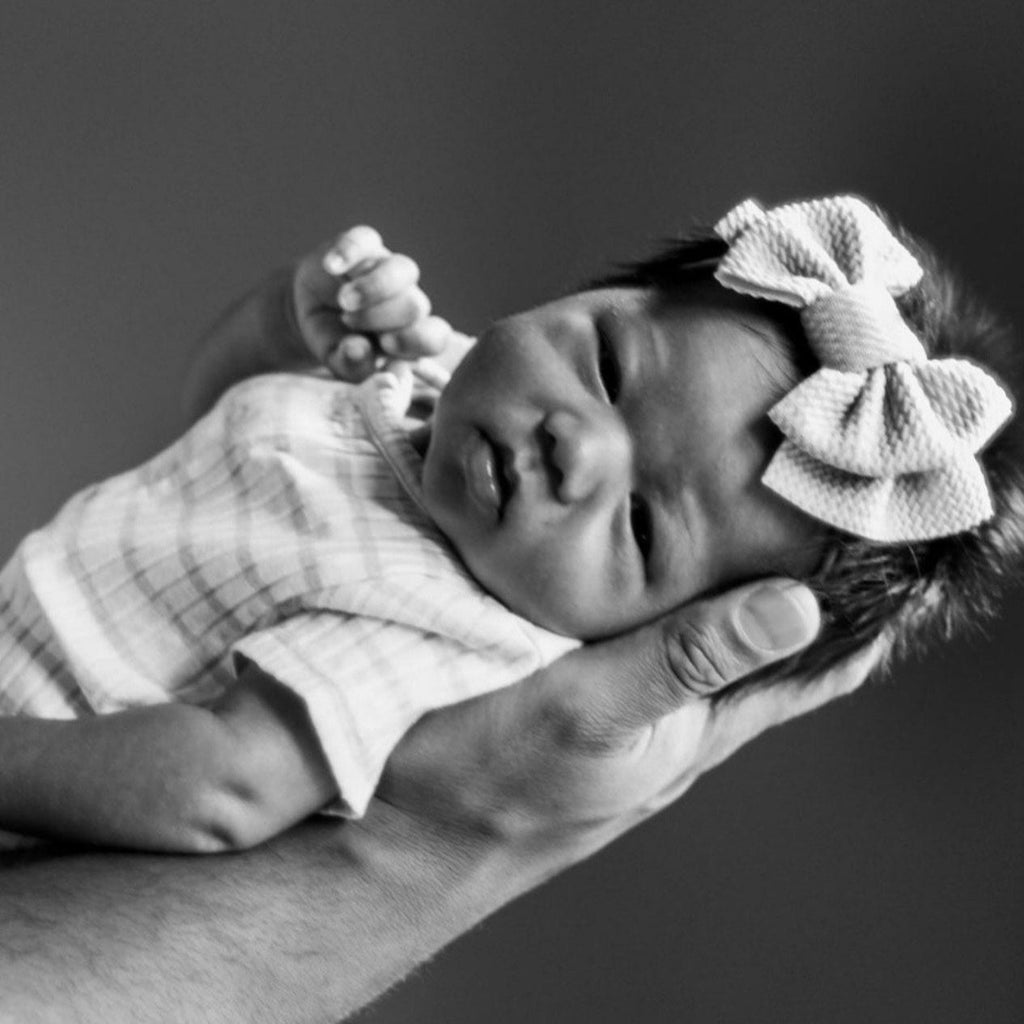 Baby held in hand with bow