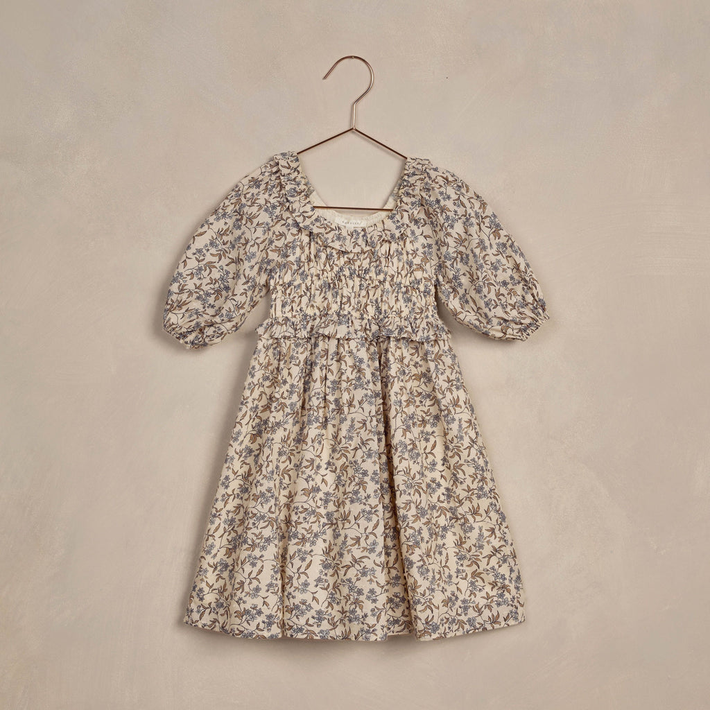 flatlay of junie dress blue floral on beige background 