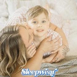 Lady kissing little boys cheek on bed