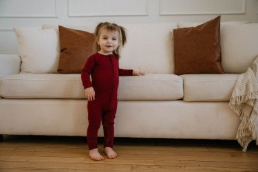 one piece barberry sleepwear on little girl beside white couch