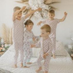 4 kids jumping on bed in pjs with flowers on chairs