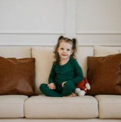 girl sitting on cream couch with brown cushions in green pj