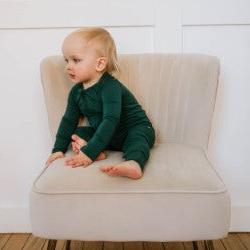 baby sitting on cream chair with green sleeper